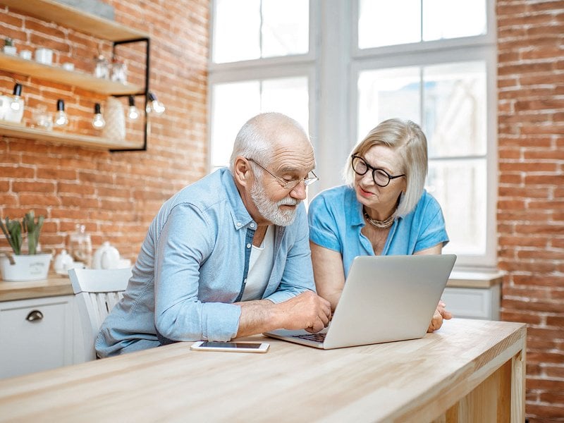 Älteres Paar schaut in der Küche auf einen Laptop
