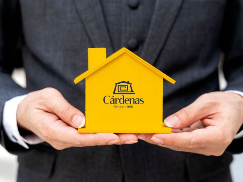 Conseiller immobilier avec une petite maison en bois jaune dans les mains