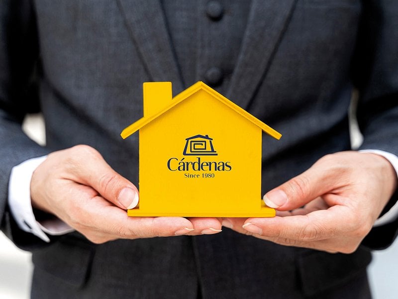 Immobilienberater mit einem gelben Holzhaus in seinen Händen