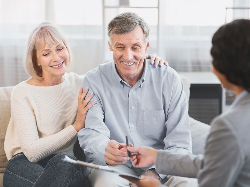 Couple heureux avec conseiller sur le point de signer un contrat