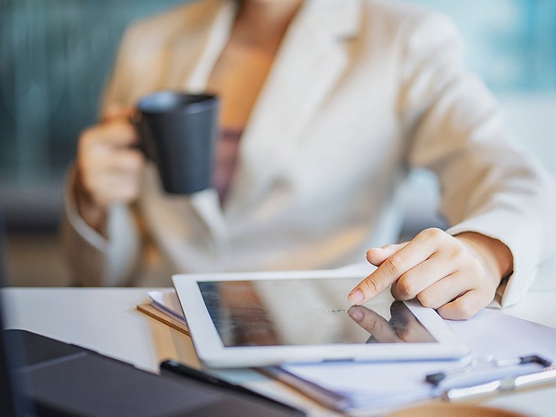 Vrouw met koffiemok die Ipad controleert