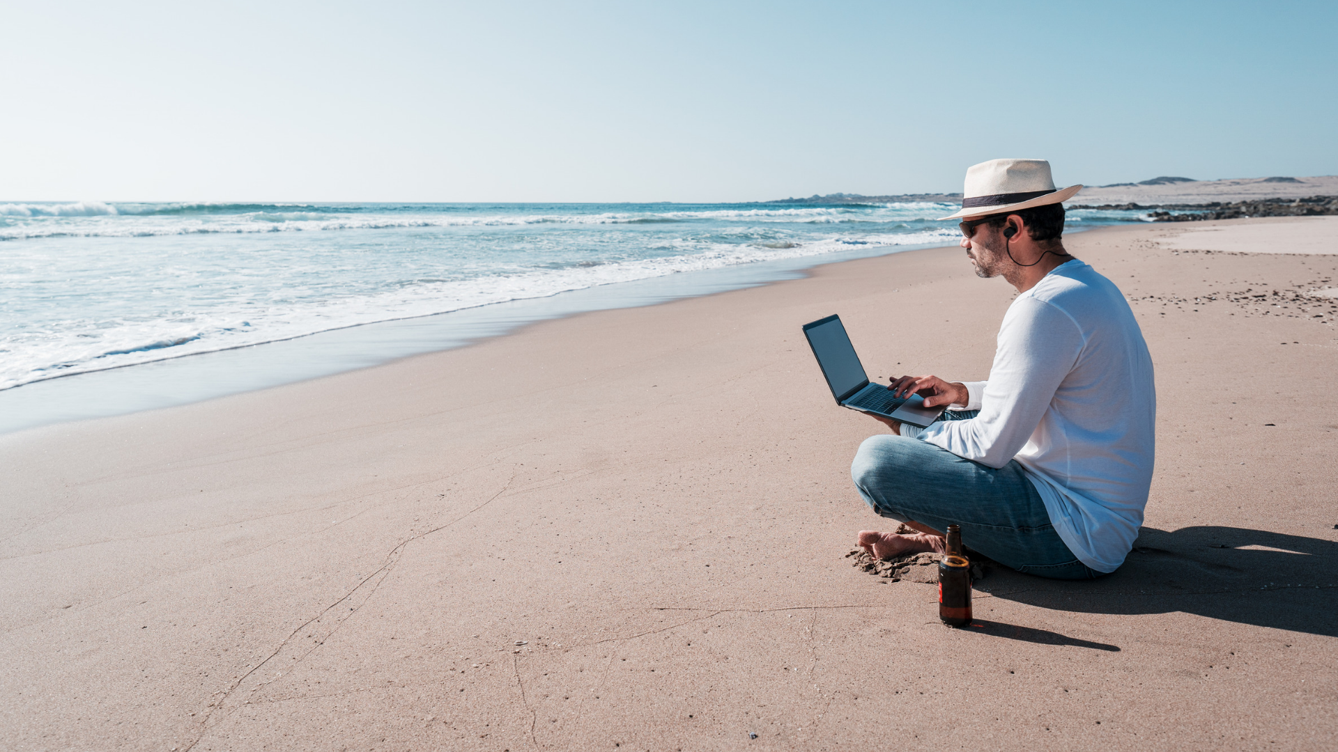 Hombre trabajando con portátil en la playa