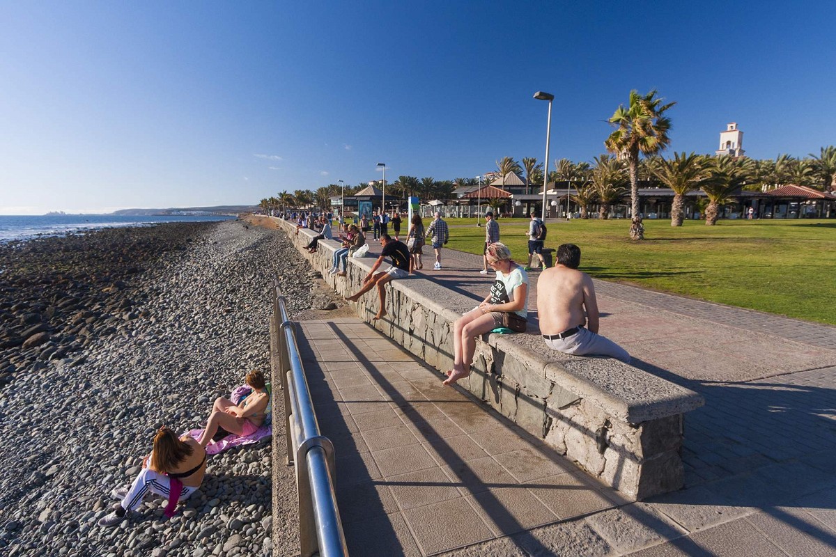 Maspalomas, Gran Canaria, folk som nyter solen på strandpromenaden i Meloneras