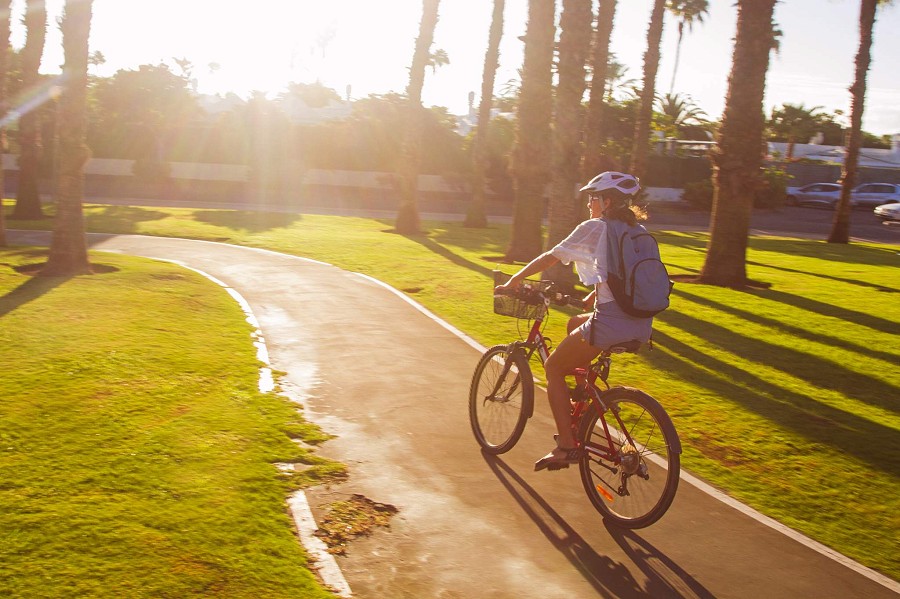 Maspalomas, Gran Canaria, Frau auf dem Fahrrad entlang der Sonnenland-Promenade