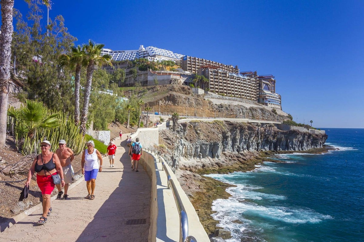 Puerto Rico, Gran Canaria, människor som går längs strandpromenaden mot Amadores