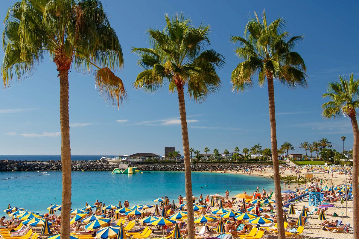 Puerto Rico, Gran Canaria, Strandbesucher an der Playa de Amadores mit Palmen