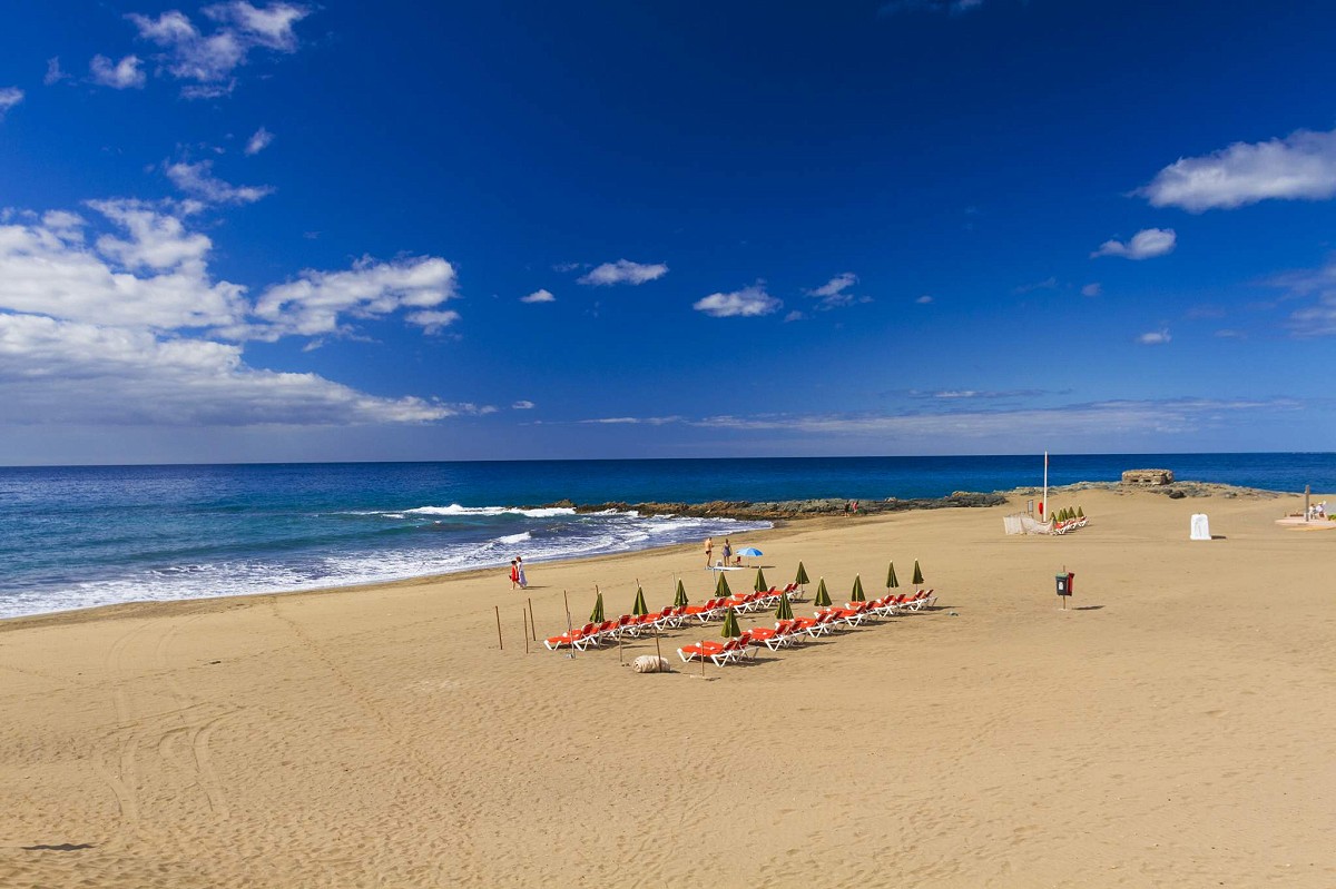 San Agustín, Gran Canaria, het strand met ligbedden en een paar wandelende mensen