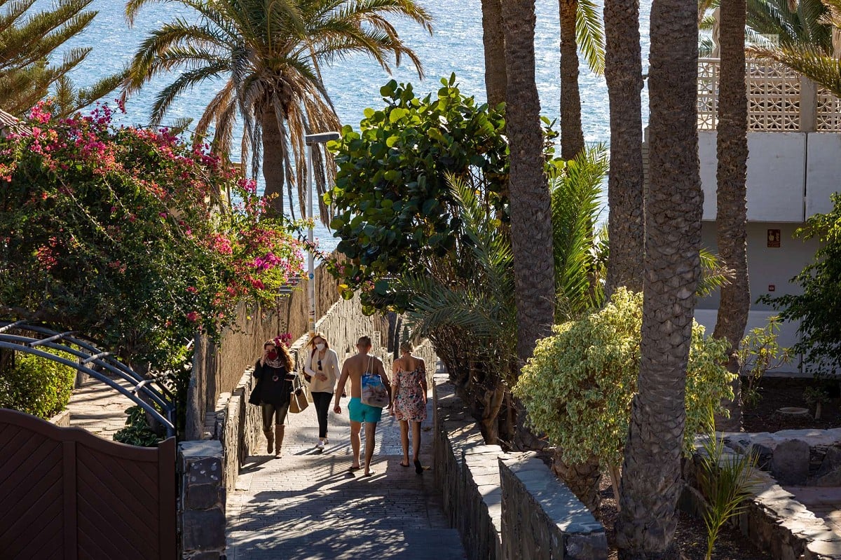 San Agustín, Gran Canaria, Spaziergänger auf der von Pflanzen umgebenen Promenade in Richtung Strand