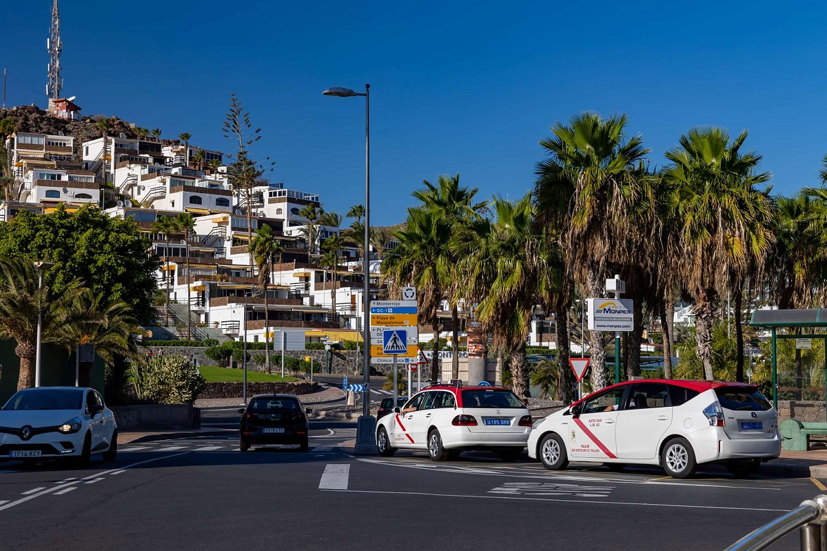 San Agustín, Gran Canaria, auf der Straße geparkte Taxis und weiße Häuser auf dem Hügel